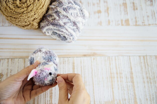 Woman making lovely bunny doll from yarn  - Easter holiday celebration concept