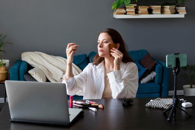 Женщина делает макияж влог со своим смартфоном