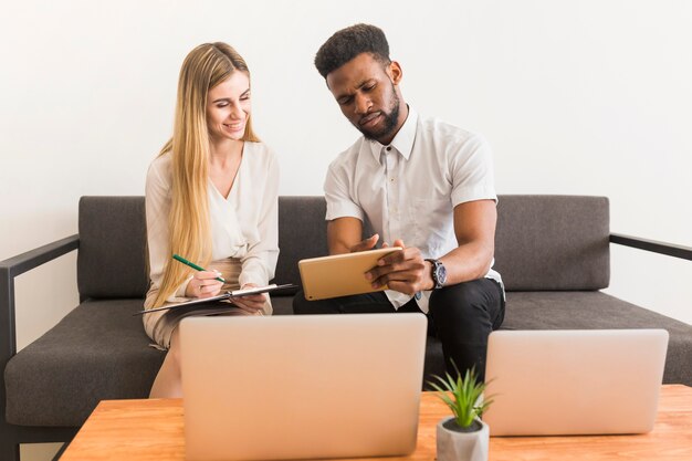 Woman making notes with working with man