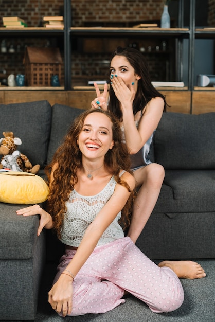 Woman making peace sign on her female friend's head