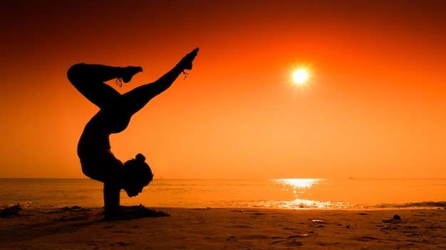 Woman making pine on the beach at sunset