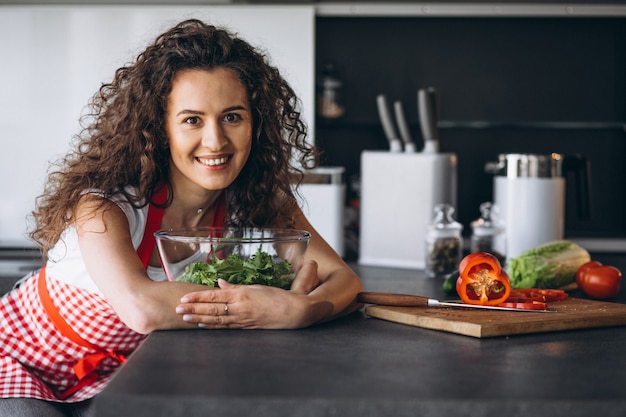 Free photo woman making salad at the kitchen