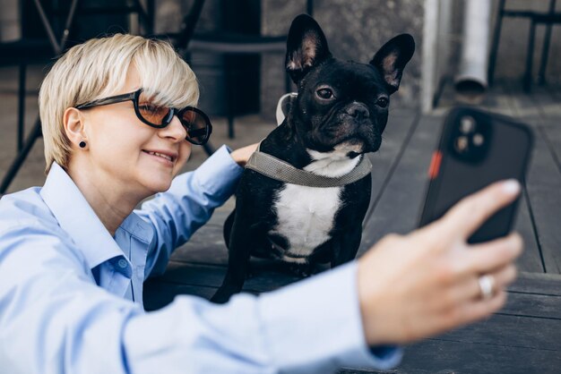 Woman making selfie photo with her pet french bulldog