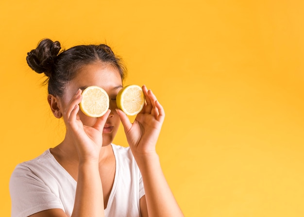 Free photo woman making sunglasses from halves of lemon