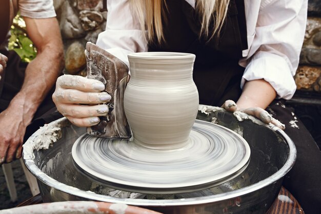 Женщина делает вазу из глины