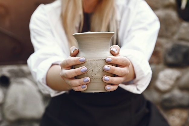 Free photo woman making a vase with clay