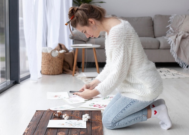 Free photo woman making a vlog of her paintings at home