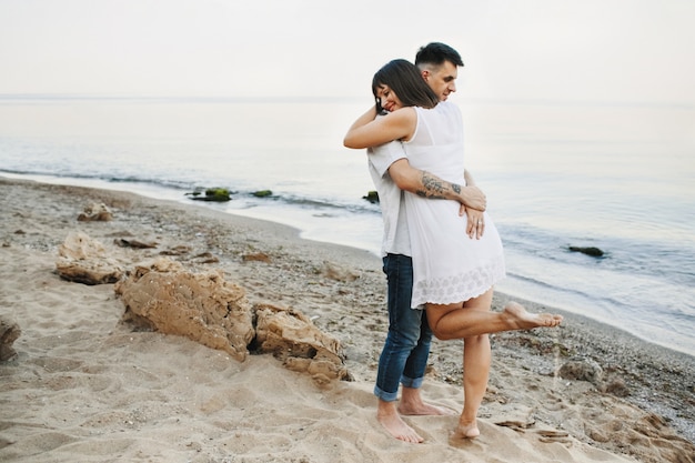 Woman and man are hugging on the beach near the sea