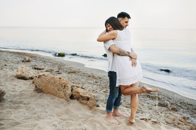 Женщина и мужчина обнимаются на пляже у моря