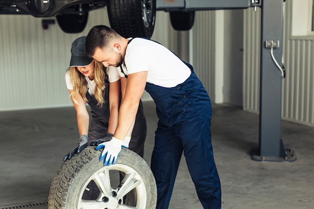 Woman and man at auto service changing wheels