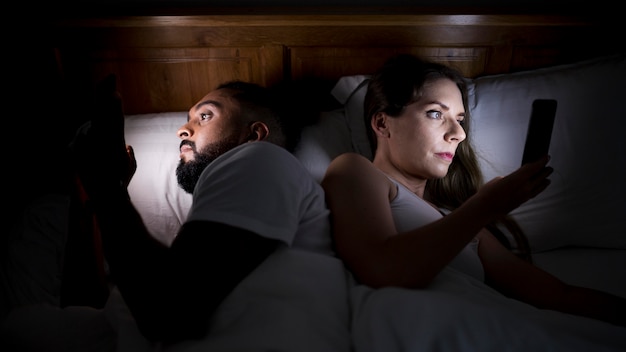 Woman and man checking their phones before sleeping