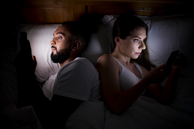 Женщина и мужчина проверяют свои телефоны перед сном