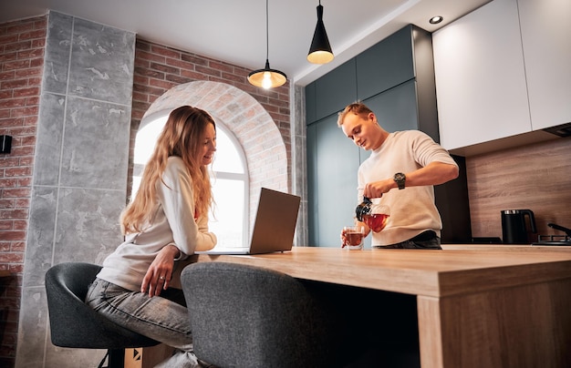 Woman and man drinking tea and watching video in laptop