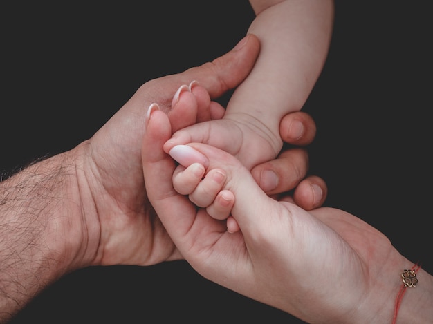 Woman and man holding newborn baby's hand