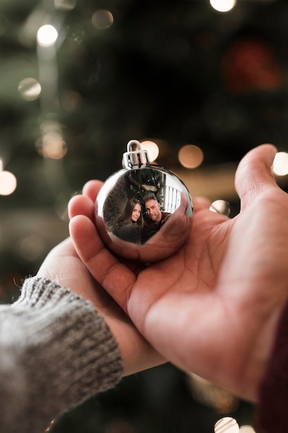 Woman and man holding ornament ball with reflection