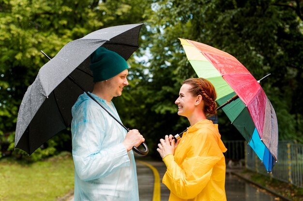 Woman and man looking at each other while holding their umbrellas