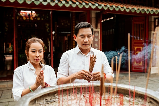 Woman and man praying at the temple with burning incense