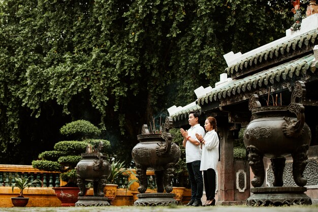 燃える線香でお寺で祈る女と男