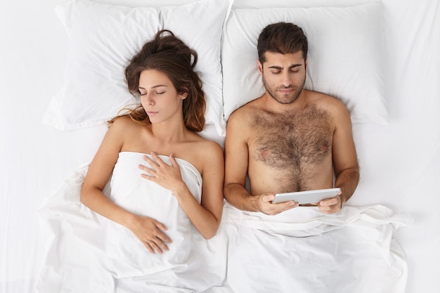 Woman and man sitting in bed top view