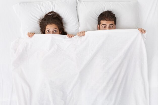 Woman and man sitting in bed top view