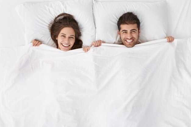 Woman and man sitting in bed top view