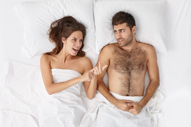 Woman and man sitting in bed top view