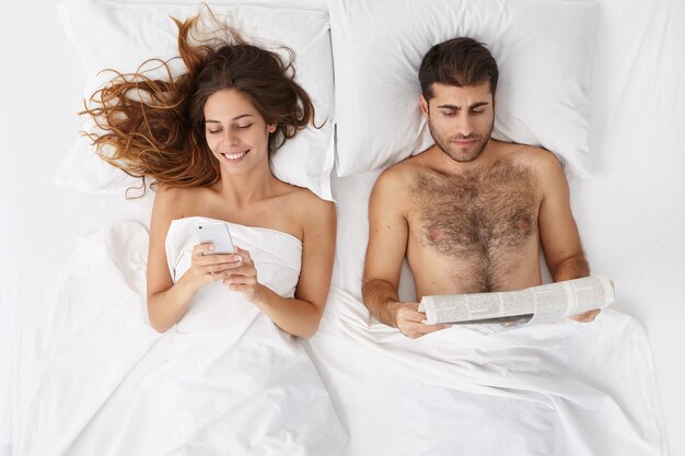 Woman and man sitting in bed top view