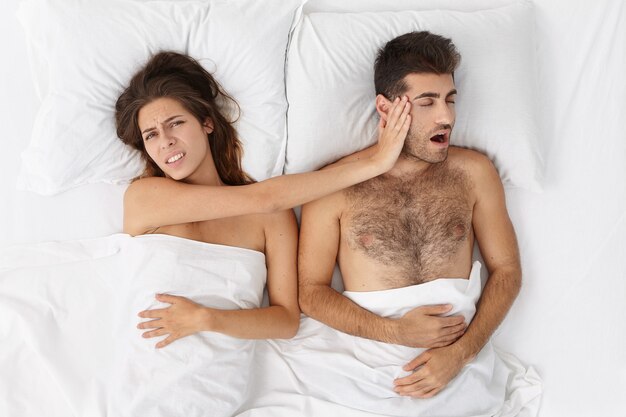 Woman and man sitting in bed top view