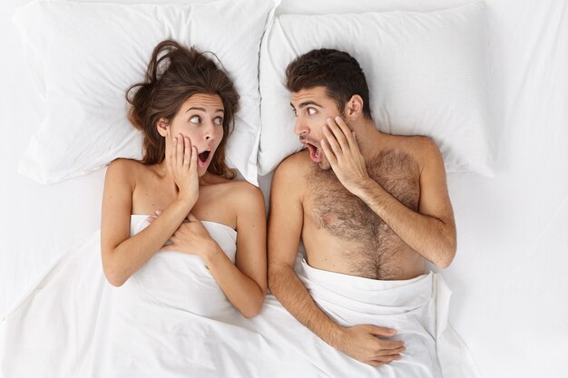 Woman and man sitting in bed top view