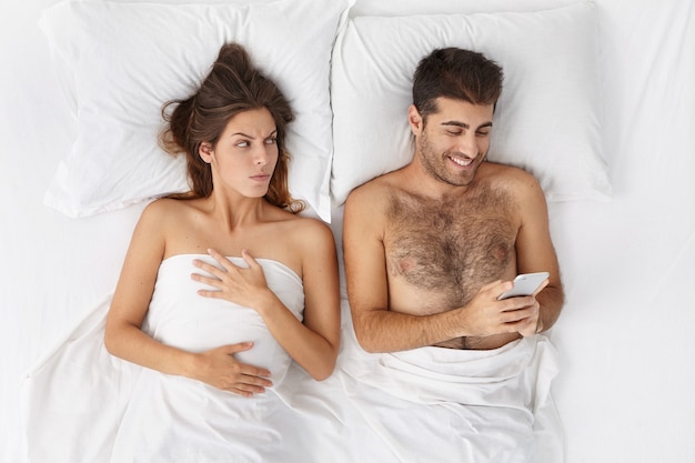 Woman and man sitting in bed top view