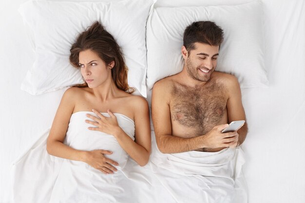 Woman and man sitting in bed top view