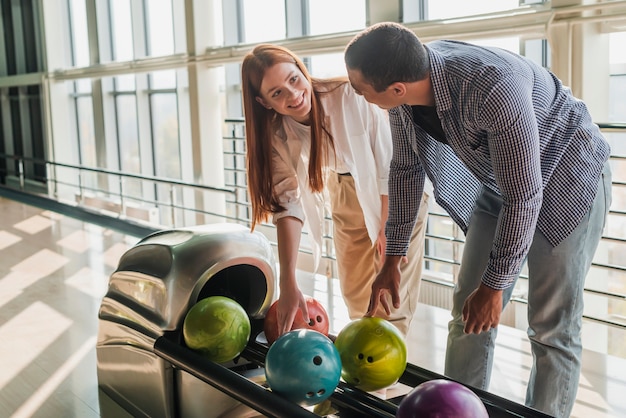 Foto gratuita donna ed uomo che prendono le palle da bowling variopinte