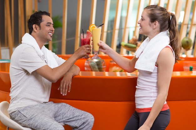 Woman and man toasting with fruit juices in a bar