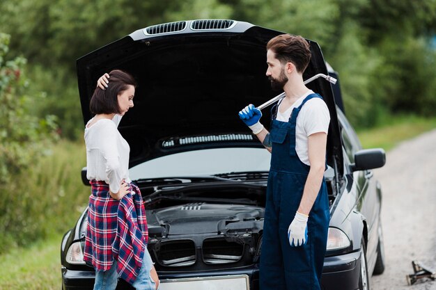 Woman and man with open car hood