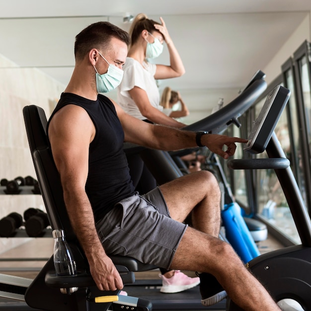 Woman and man working out at the gym with medical masks
