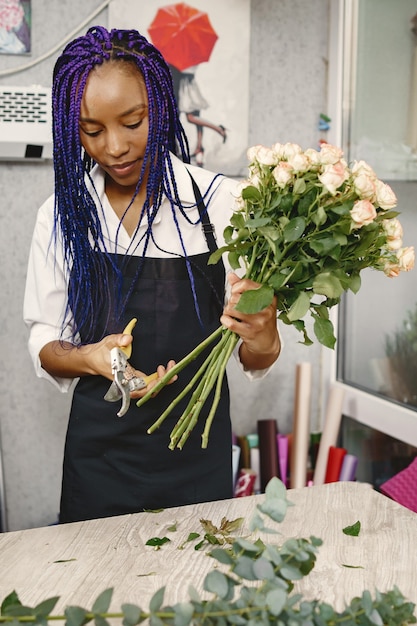 Woman manager standing at workplace. Lady with plant in hands. Famale cutting flowers. Florist concept.