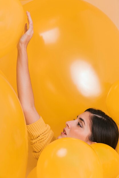 Woman between many yellow balloons