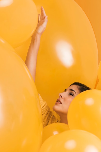 Woman between many yellow balloons