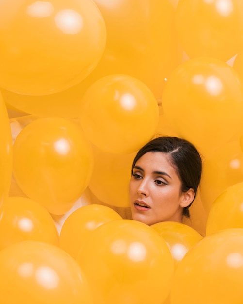 Woman between many yellow balloons