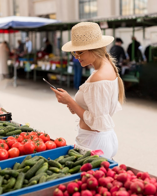 Женщина на рынке, используя свой мобильный телефон