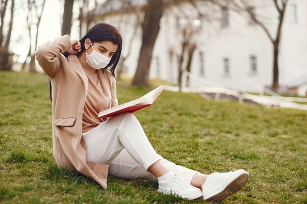 Woman in a mask sitting on a grass