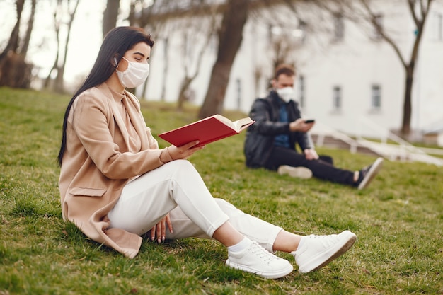 Woman in a mask sitting on a grass