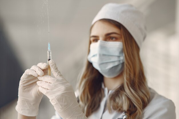 Woman in a mask and uniform holding a syringe in her hands