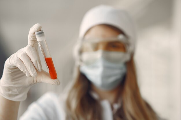 Woman in a mask and uniform holding a tube in her hands