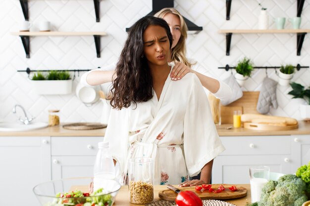 Woman massages african woman shoulders, she feel pain