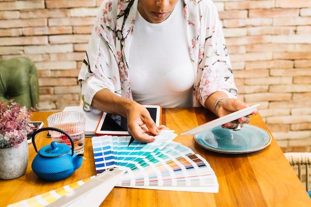 Woman matching the ceramic plate with color swatch on wooden table