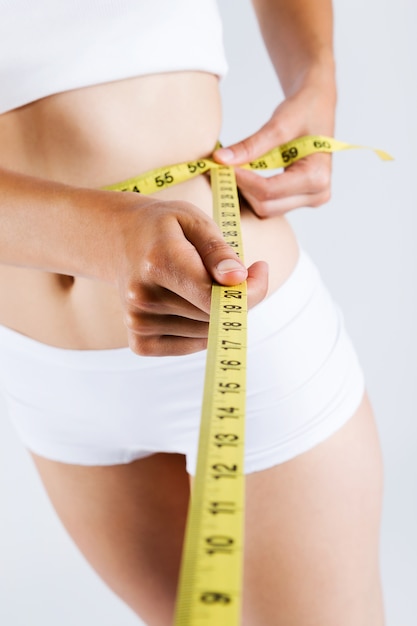 Woman measuring her slim body. Isolated on white background.