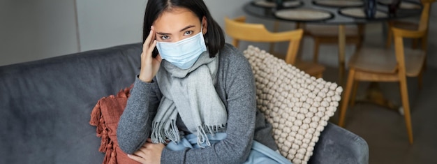 Foto gratuita la donna con la maschera medica resta a casa con i dispositivi di protezione individuale mentre prende l'influenza