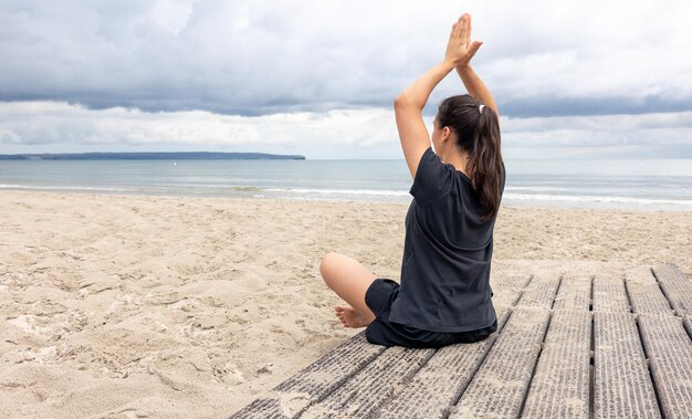 A woman meditates while sitting on the seashore
