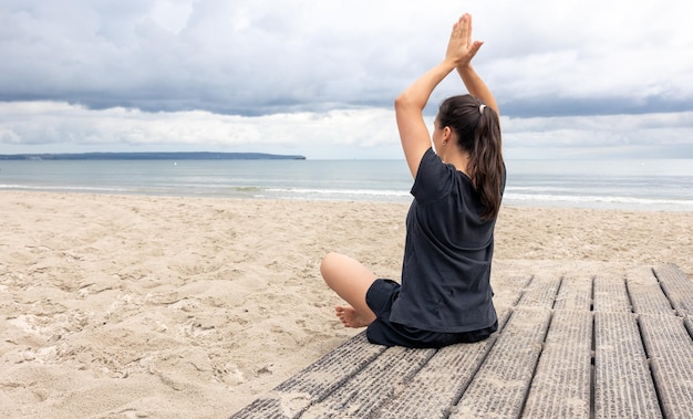 Женщина медитирует, сидя на берегу моря
